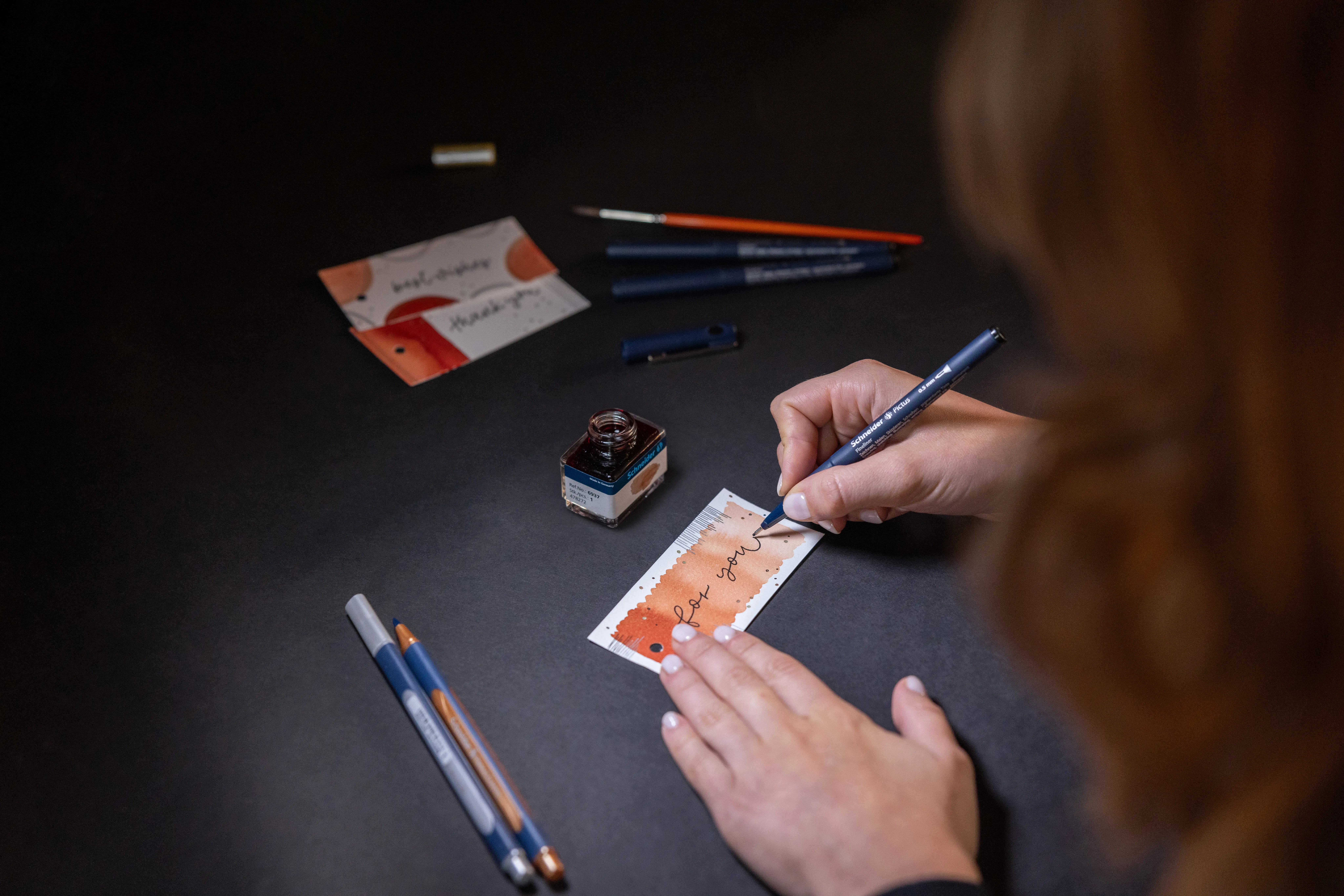 Frau gestaltet Geschenkanhänger aus dem DIY-Set von Schneider