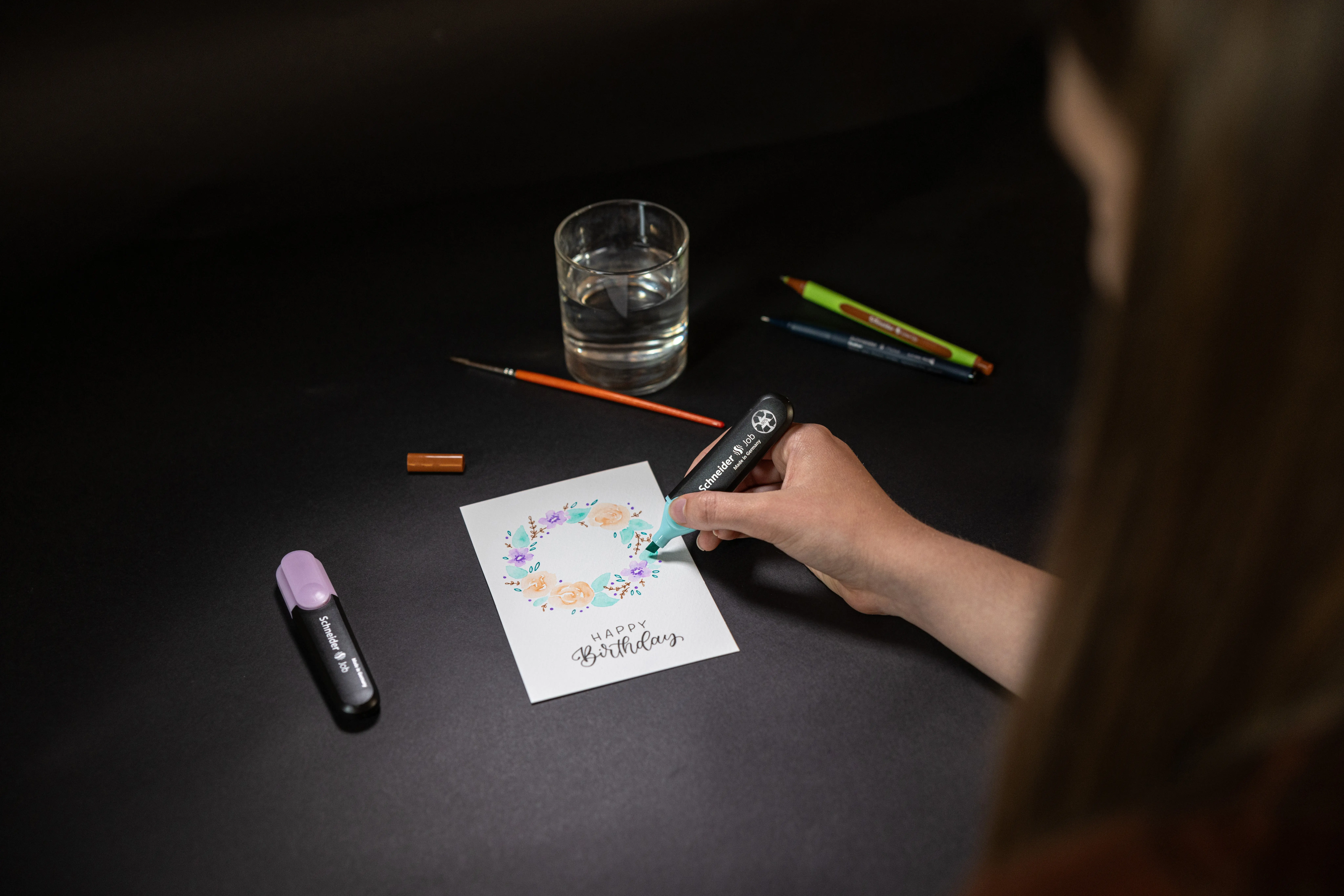 Frau gestaltet Postkarte aus dem DIY-Set von Schneider